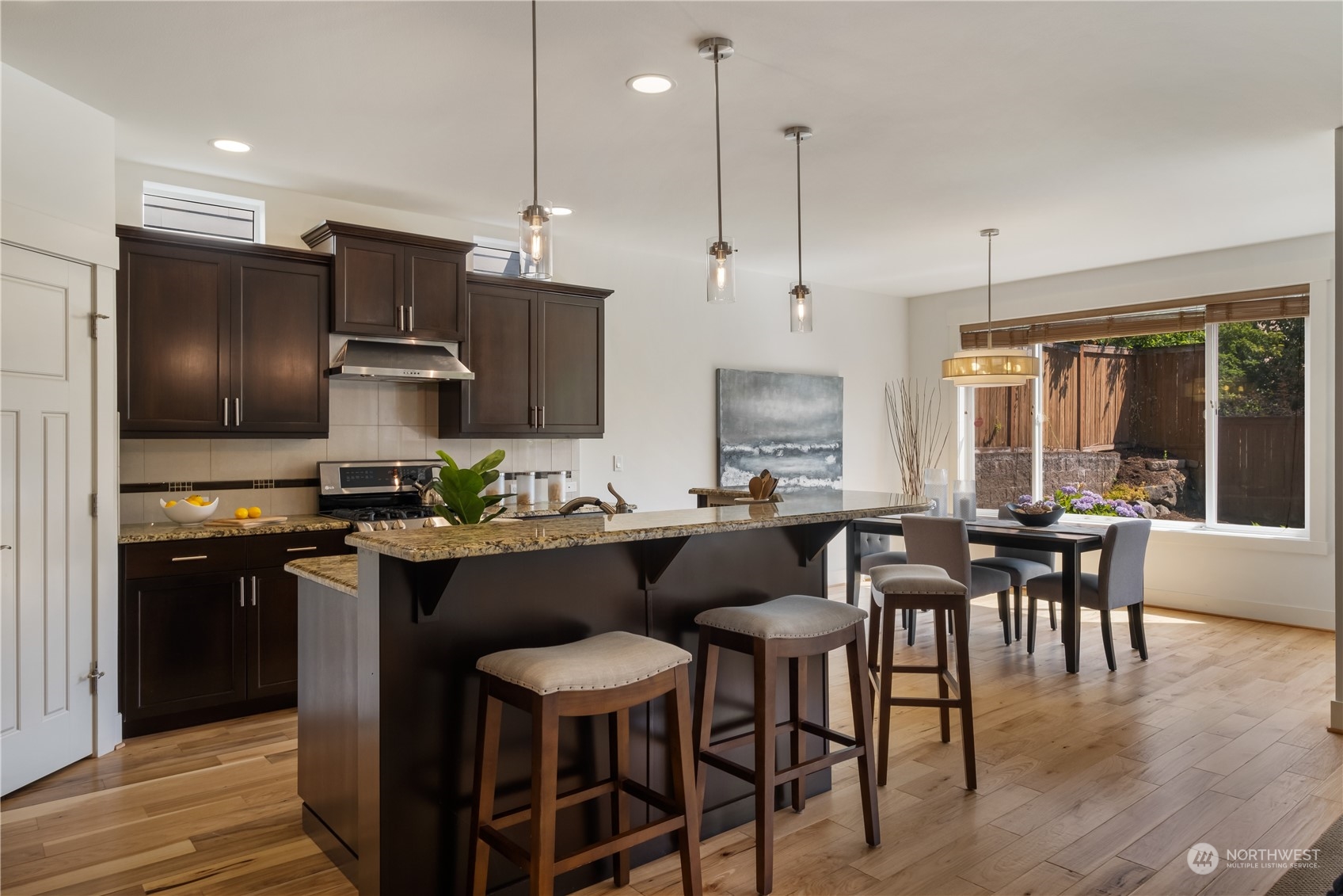 5525 Northeast 7th Place Renton, WA 98059 - Photo 7 of 30 a kitchen with stainless steel appliances kitchen island granite countertop a table chairs stove and microwave