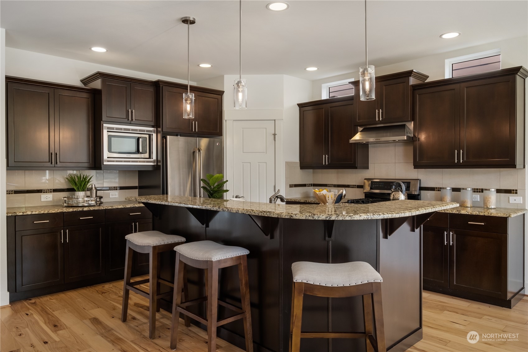 5525 Northeast 7th Place Renton, WA 98059 - Photo 8 of 30 a kitchen with stainless steel appliances granite countertop a sink a stove a refrigerator a kitchen island with chairs and wooden cabinets