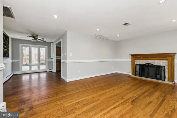 an empty room with wooden floor fireplace and windows