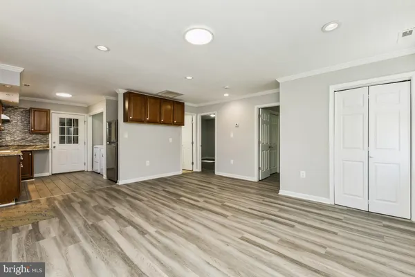 a view of an empty room with kitchen and a window