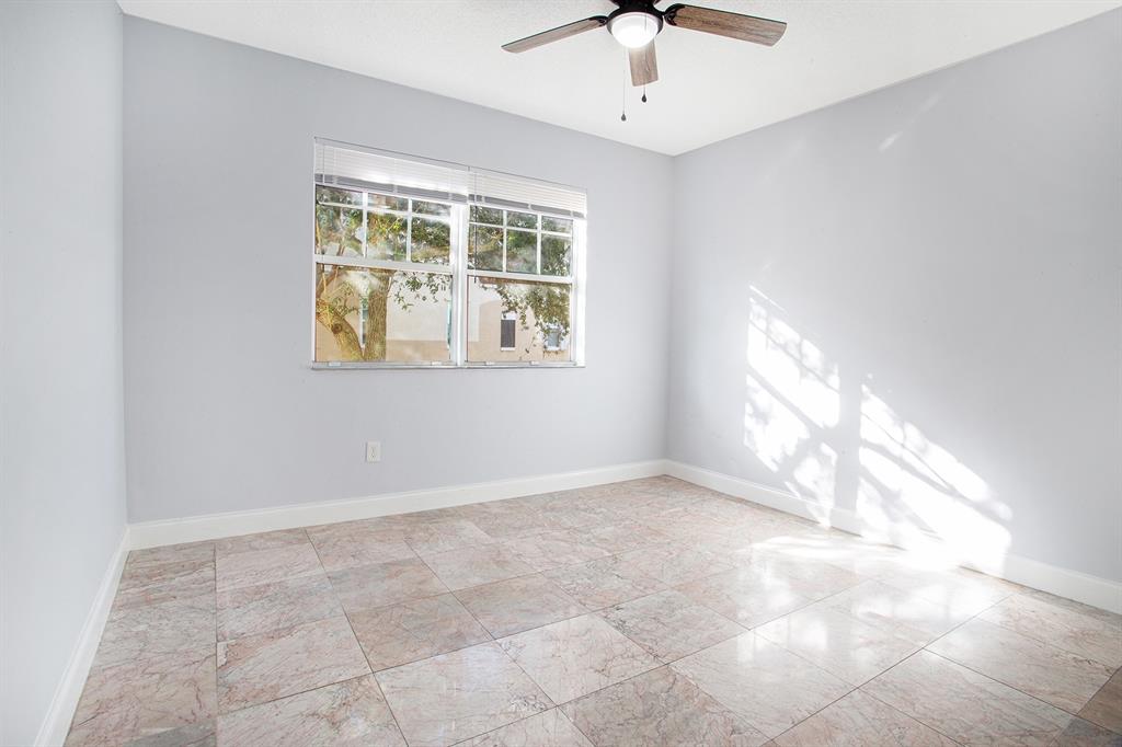 5860 West Sample Road, Unit 204 Coral Springs, FL 33067 - Photo 12 of 36 an empty room with windows and chandelier fan