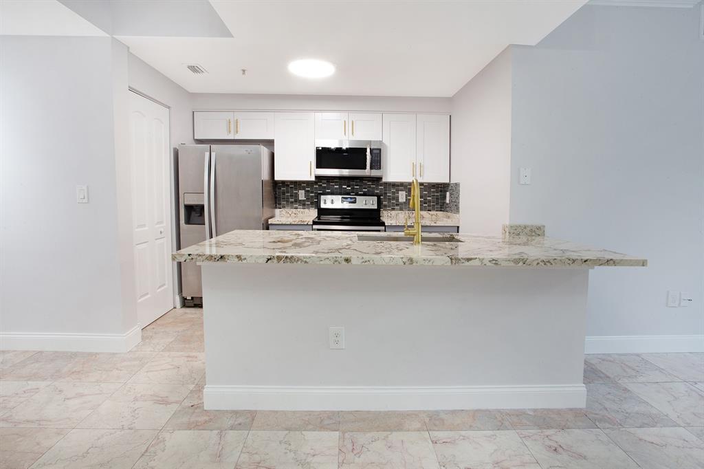 5860 West Sample Road, Unit 204 Coral Springs, FL 33067 - Photo 2 of 36 a kitchen with kitchen island stainless steel appliances a refrigerator stove microwave and sink