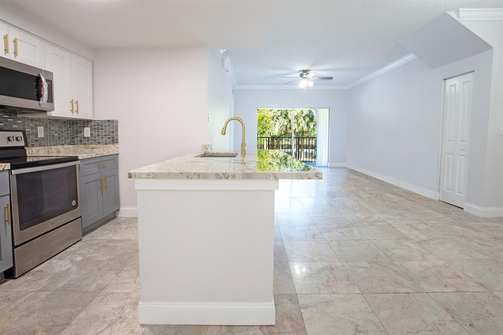 5860 West Sample Road, Unit 204 Coral Springs, FL 33067 - Photo 4 of 36 a kitchen with stainless steel appliances granite countertop a stove a sink and a microwave