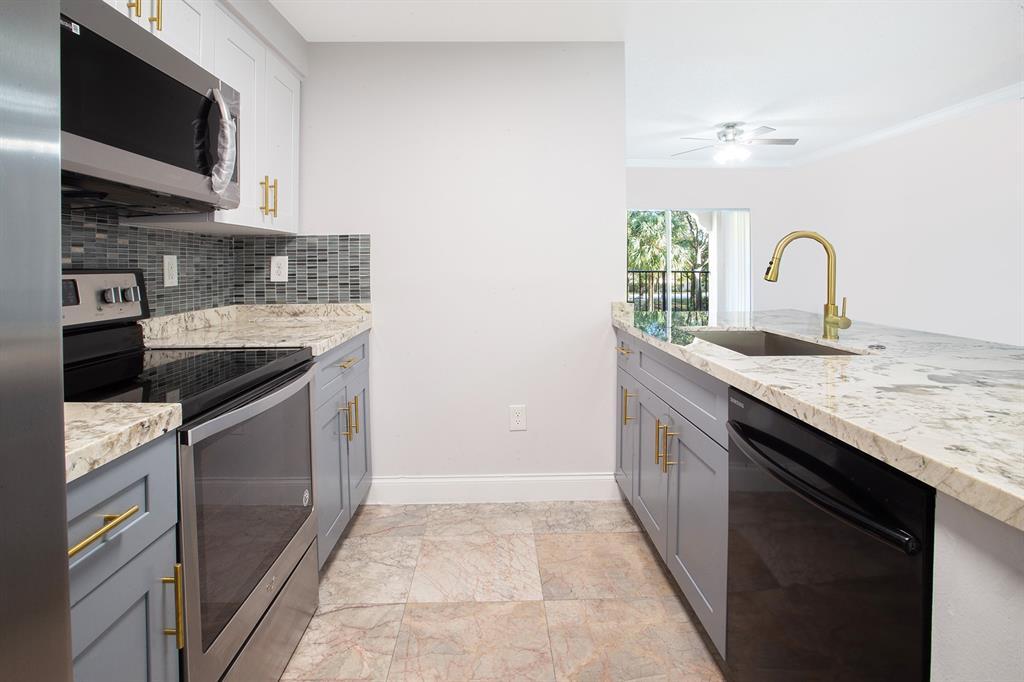 5860 West Sample Road, Unit 204 Coral Springs, FL 33067 - Photo 10 of 36 a kitchen with granite countertop a sink and a stove top oven
