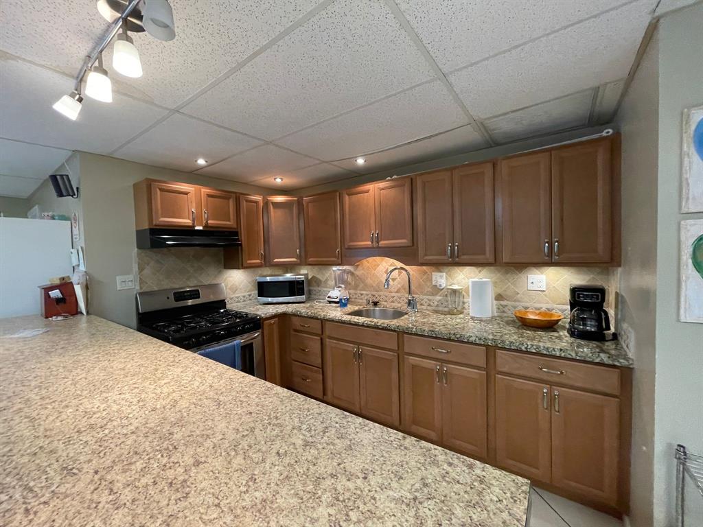 250 Northeast 20th Street, Unit 210 Boca Raton, FL 33431 - Photo 38 of 50 a kitchen with granite countertop wooden cabinets a sink and stainless steel appliances
