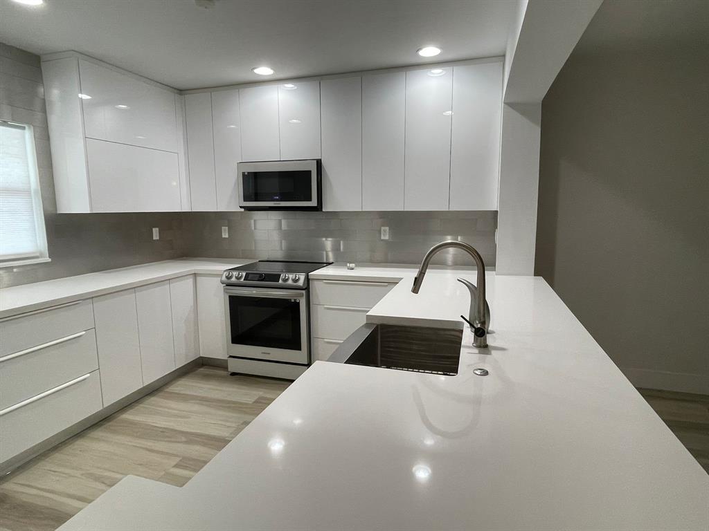 250 Northeast 20th Street, Unit 210 Boca Raton, FL 33431 - Photo 8 of 50 a kitchen with a sink a microwave and cabinets