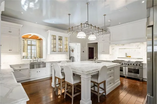 a kitchen with stainless steel appliances granite countertop a refrigerator and a wooden floor