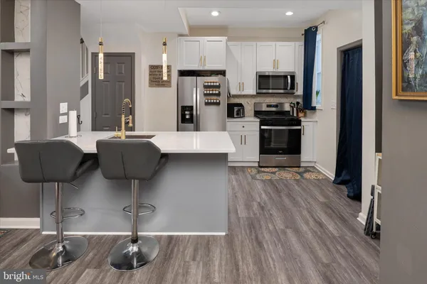 a kitchen with stainless steel appliances granite countertop a refrigerator a stove and a wooden floors