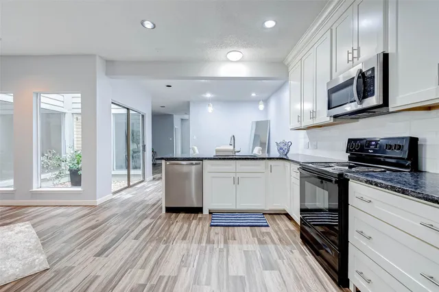 a kitchen with stainless steel appliances granite countertop a stove a sink and a microwave