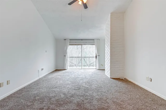 an empty room with chandelier fan and windows