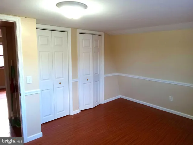 an empty room with wooden floor & closet area