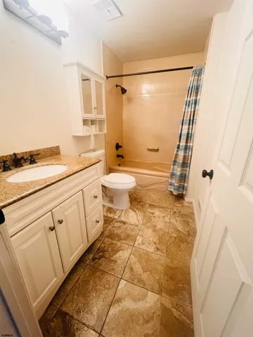a bathroom with a granite countertop sink a toilet and a shower