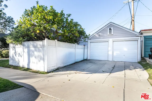 a view of a white house with a small yard and large parking space