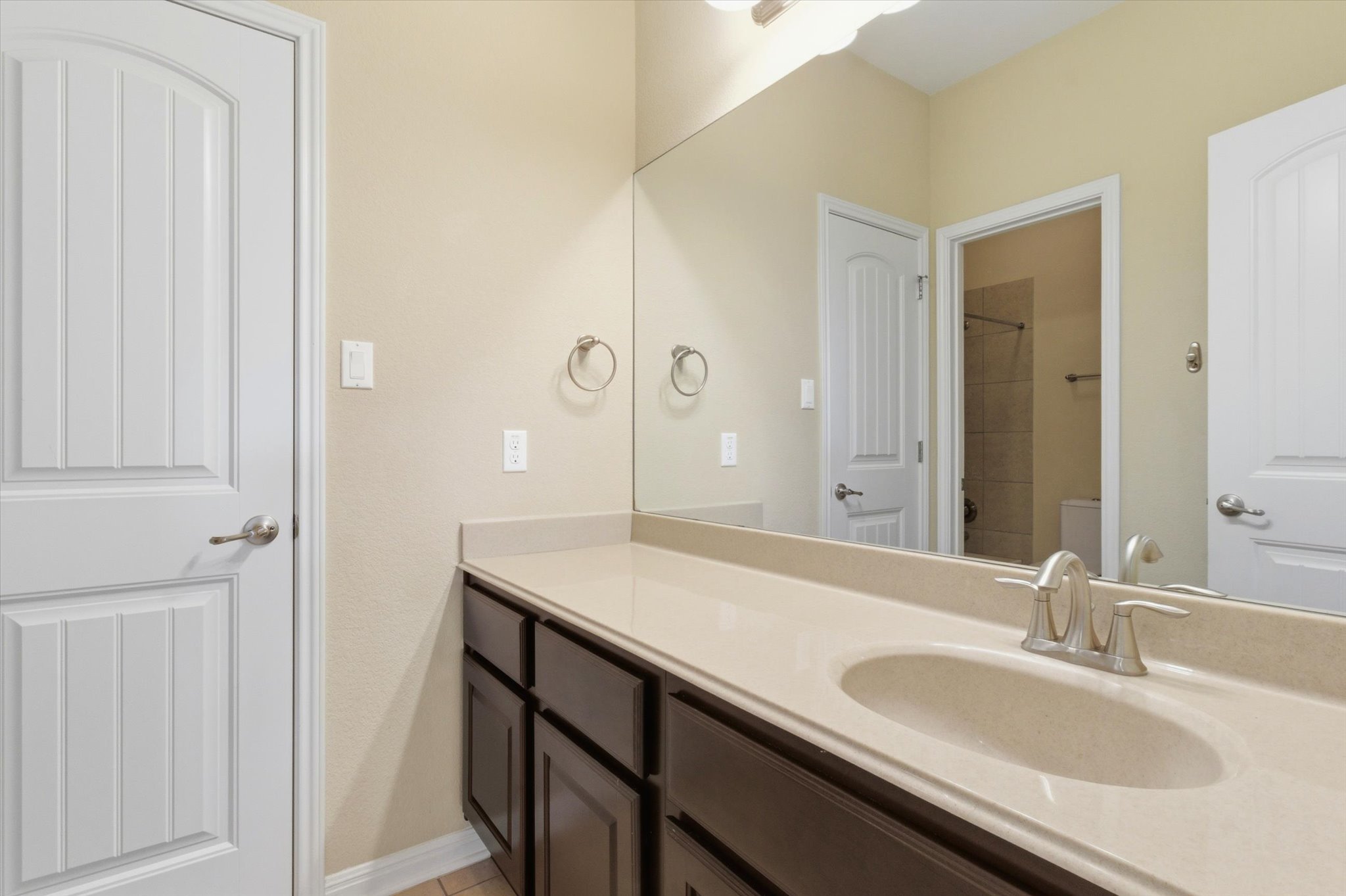 1511 Rimstone Drive Cedar Park, TX 78613 - Photo 28 of 39 A well-lit bathroom vanity features a broad mirror, dark wood cabinetry, and a clean integrated sink.
