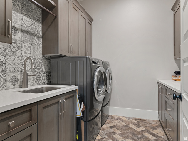 641 West 500 South Midway, UT 84049 - Photo 20 of 52 Utility space featuring patterned tile flooring, a stainless steel sink with a high-arc faucet, quartz countertops, extensive cabinetry, and decorative backsplash tiling