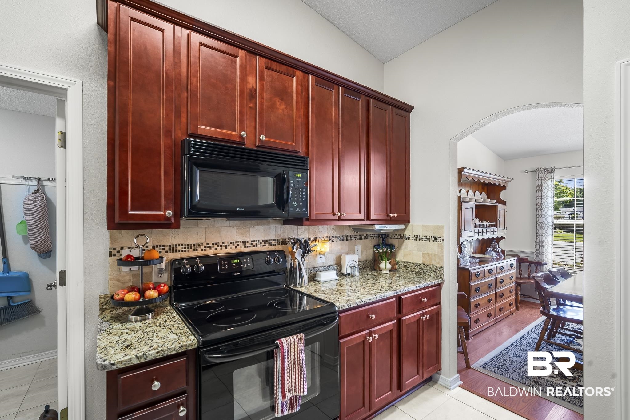1802 South Bay Street Foley, AL 36535 - Photo 14 of 30 Kitchen featuring black appliances, dark brown cabinets, arched walkways, and decorative backsplash
