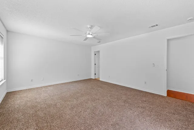 a view of an empty room with a chandelier fan