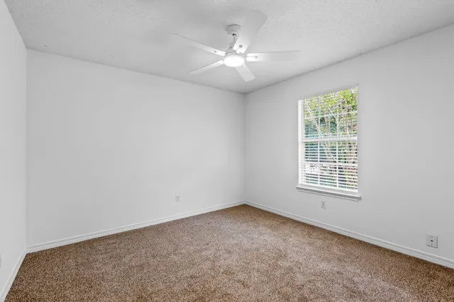 an empty room with windows and chandelier fan