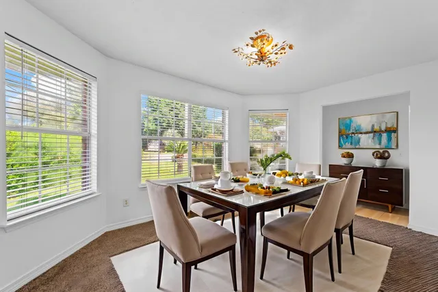 a dining room with furniture a large window and wooden floor
