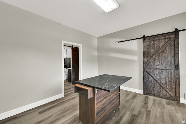 716 East Factory Street Garland, UT 84312 - Photo 16 of 30 Kitchen island with a dark stone countertop, wood-finish flooring, and a sliding barn door with black hardware