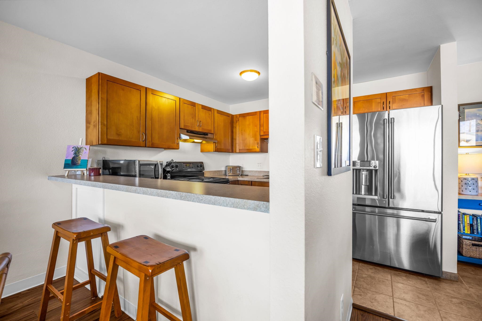 483 South Kihei Road, Unit 215 Kihei, HI 96753 - Photo 21 of 49 a kitchen with stainless steel appliances granite countertop a refrigerator a stove and a sink with granite countertops