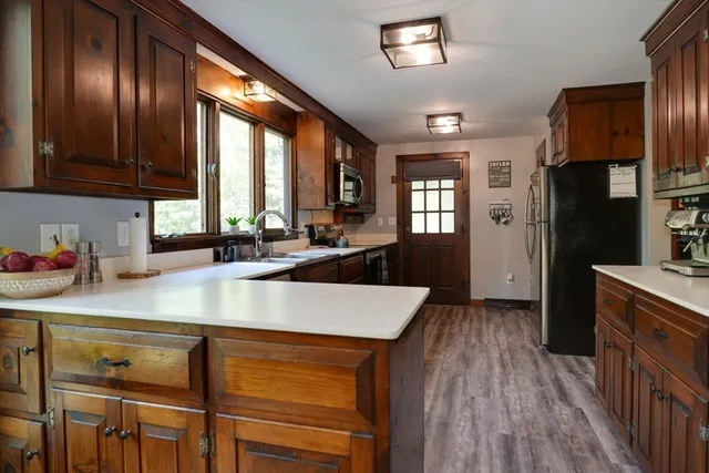 a kitchen with kitchen island granite countertop wooden cabinets a refrigerator a sink and wooden cabinets