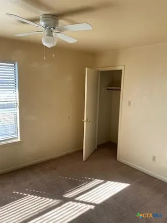 an empty room with a ceiling fan and window