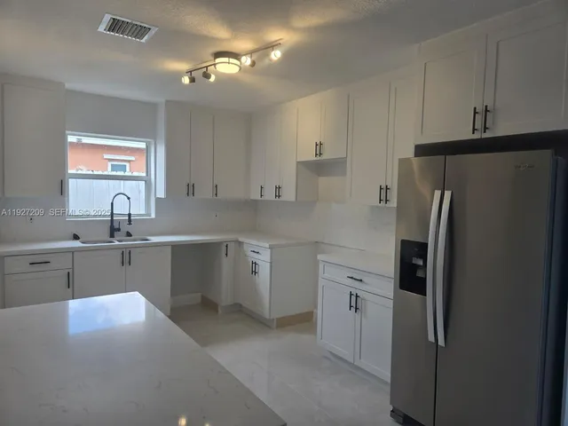 a kitchen with a refrigerator sink and cabinets