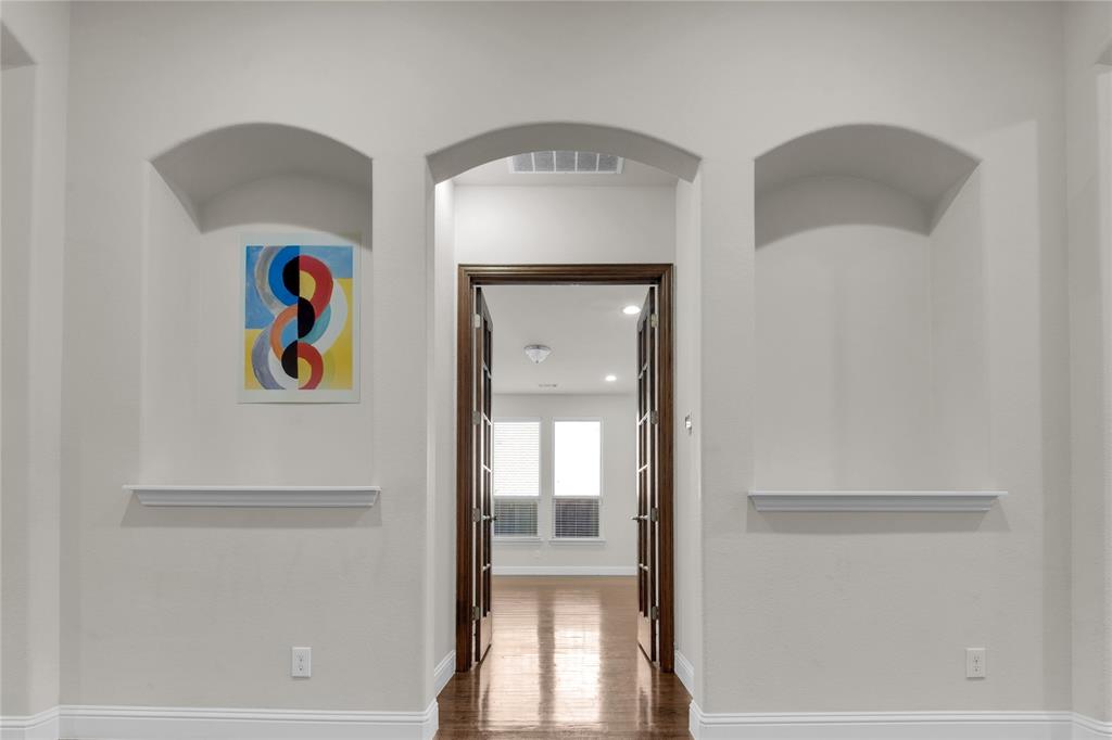 1011 Prairie Ridge Lane Arlington, TX 76005 - Photo 18 of 32 Arched wall cutouts featuring integrated shelving, dark wood-finish French doors, and wood-finish flooring
