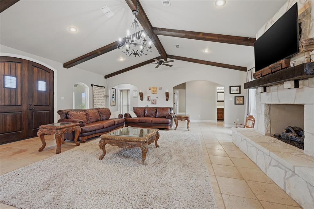 1959 Marlow Road Bells, TX 75414 - Photo 4 of 33 Living room featuring a stone fireplace, arched walkways, suspended lighting, and a ceiling fan