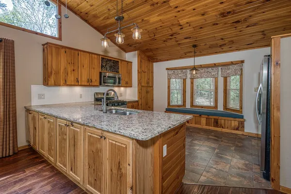 a kitchen with stainless steel appliances granite countertop a stove top oven a sink dishwasher a refrigerator and a microwave oven