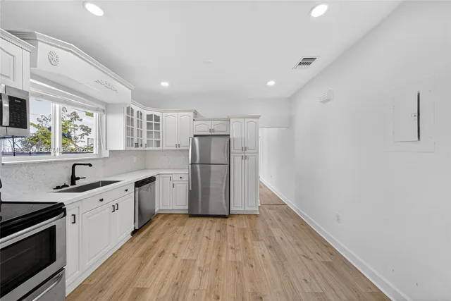 a large kitchen with a wooden floor a sink stainless steel appliances and cabinets