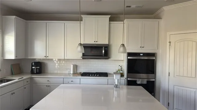 a kitchen with stainless steel appliances granite countertop a stove a sink and a white cabinets