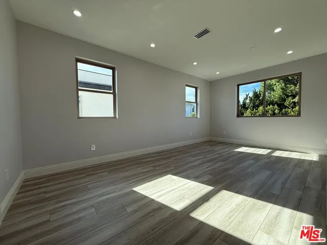 an empty room with wooden floor and natural light