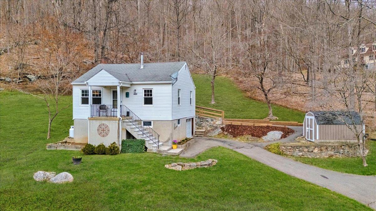 485 Sprout Brook Road Garrison, NY 10524 - Photo 1 of 1 View of front of property with an outdoor structure, an attached garage, aphalt driveway, a front yard, and a storage shed