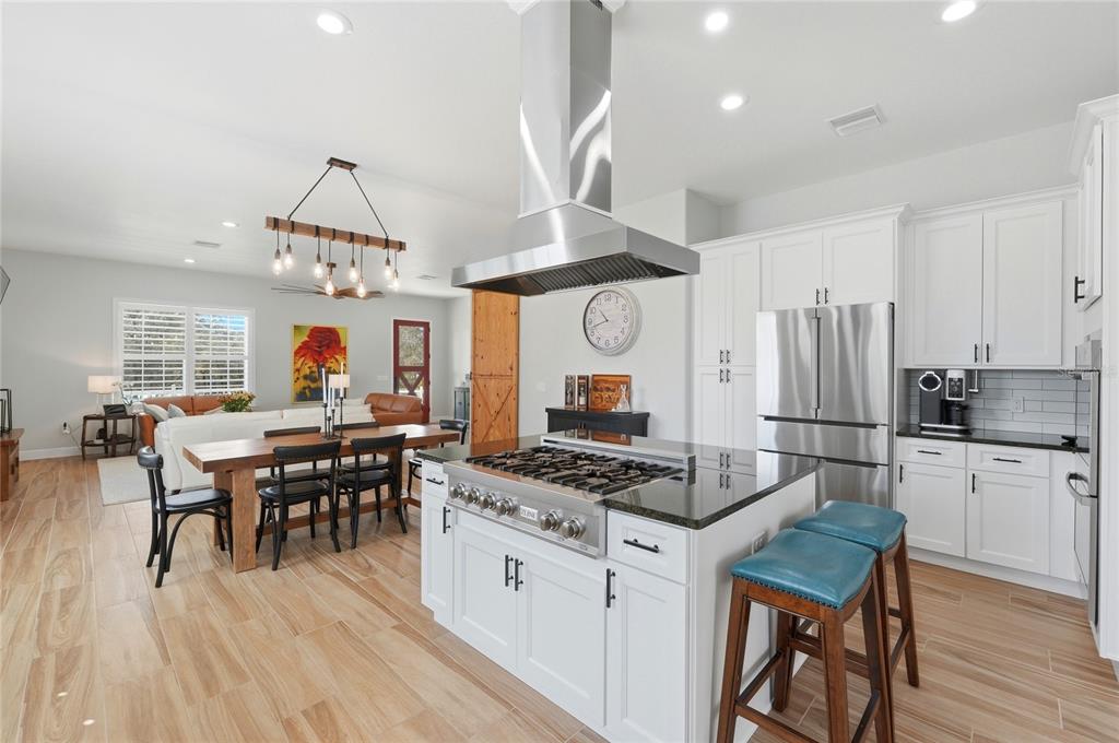 2204 Re Byrd Road Frostproof, FL 33843 - Photo 11 of 49 a kitchen with stainless steel appliances granite countertop a stove a refrigerator a kitchen island a dining table and chairs with wooden floor