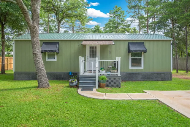 a view of a house with a yard potted plants and a large tree