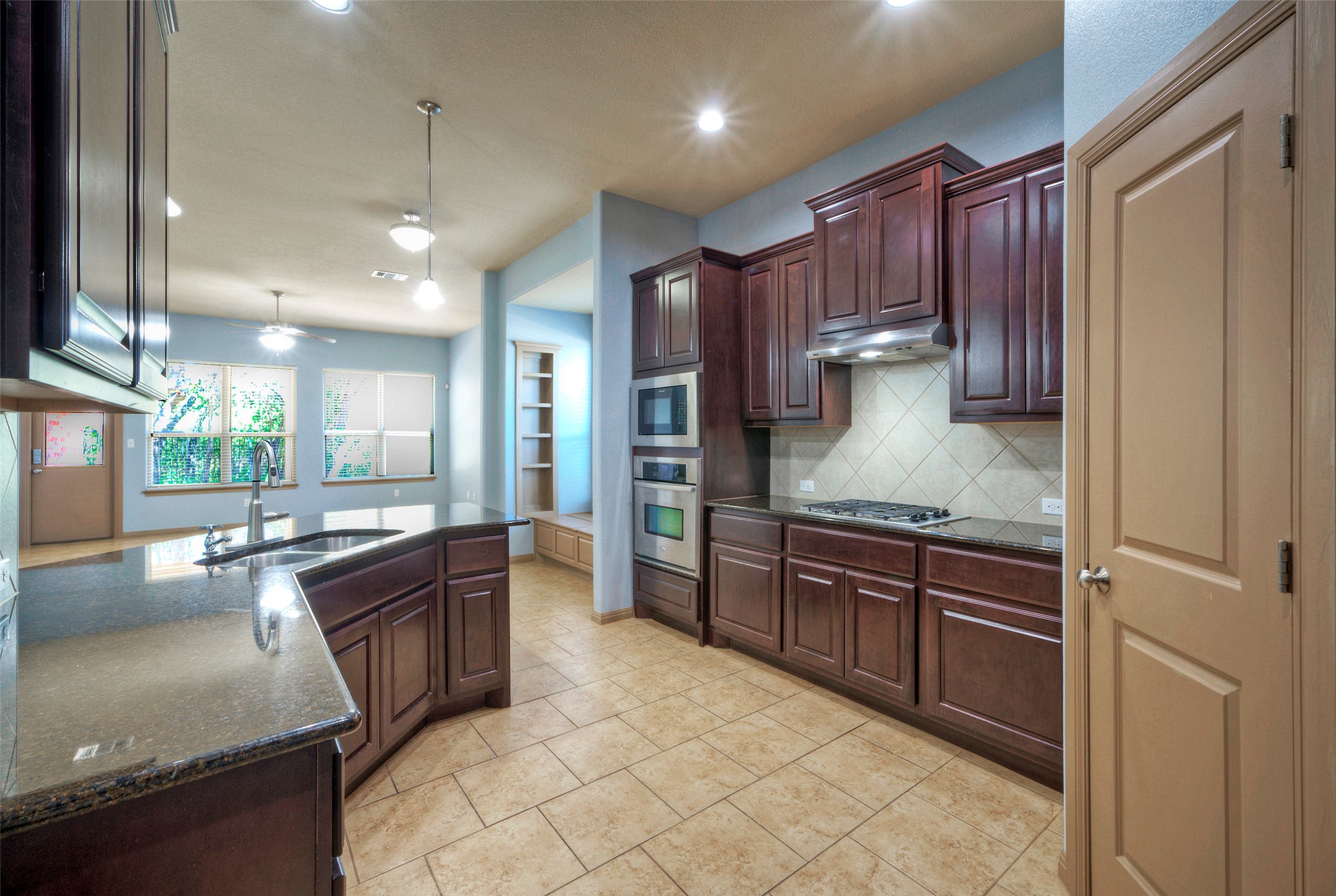 1601 Nelson Ranch Loop Cedar Park, TX 78613 - Photo 14 of 30 Rich dark wood cabinetry and stone countertops anchor this open, tile-floored kitchen.