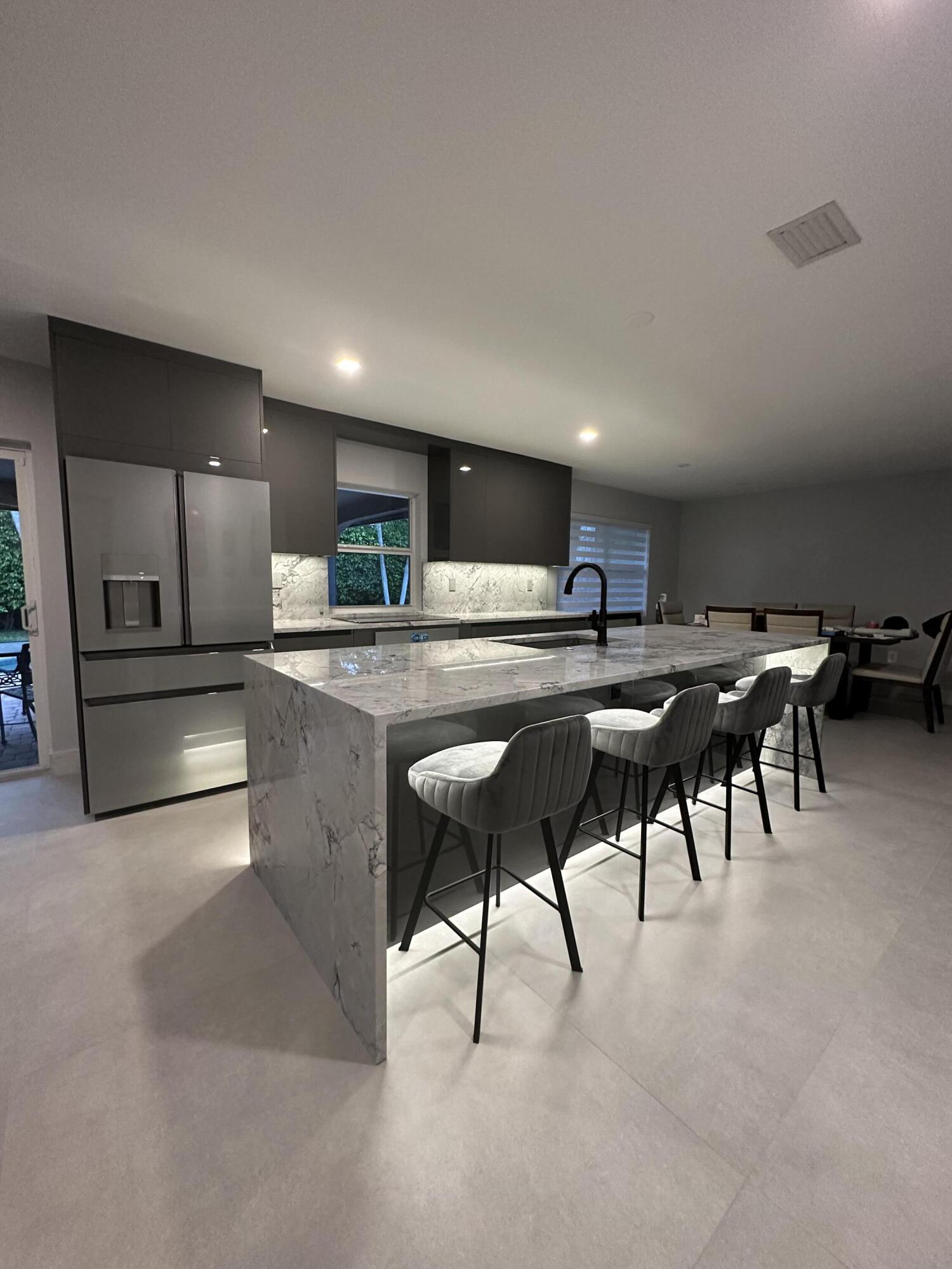 3289 Northwest 26th Avenue Boca Raton, FL 33434 - Photo 6 of 10 a kitchen with stainless steel appliances granite countertop a table chairs sink and microwave