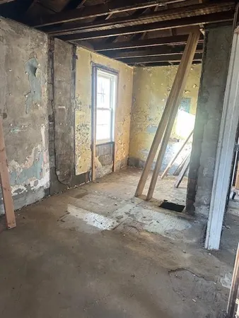 a view of an empty room with wooden floor and furniture