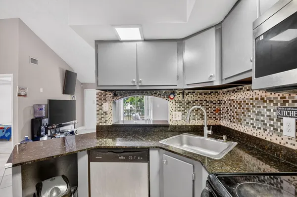 a kitchen with granite countertop a sink stainless steel appliances and cabinets