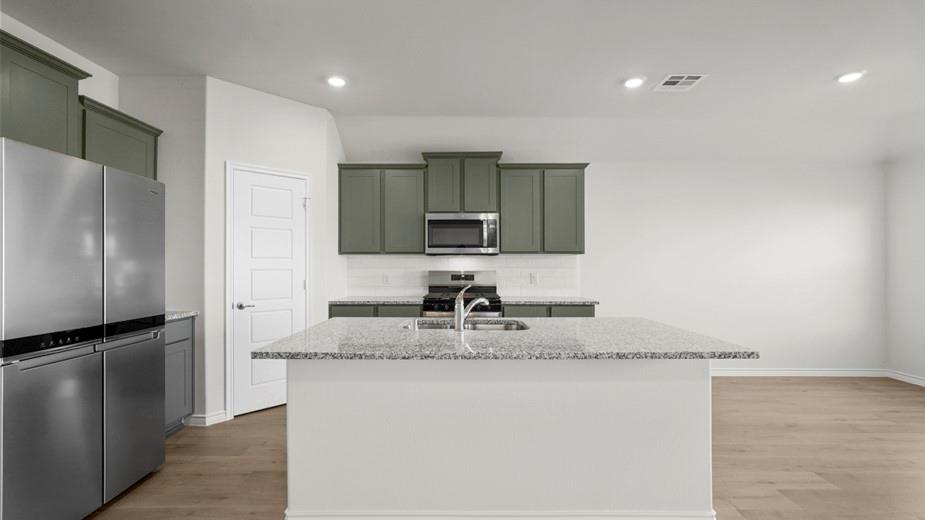 439 Epiphany Lane Lavon, TX 75166 - Photo 8 of 31 Kitchen featuring a central island with a light-toned countertop, stainless steel appliances, a subway tile backsplash, green cabinetry, and wood-finish flooring