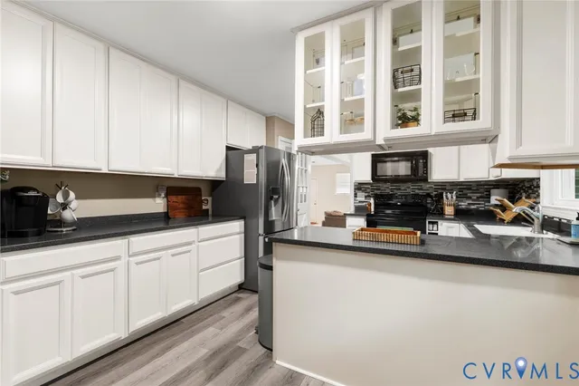 a kitchen with stainless steel appliances granite countertop a refrigerator a sink a stove and white cabinets