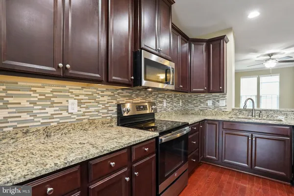 a kitchen with granite countertop stainless steel appliances a sink stove and microwave