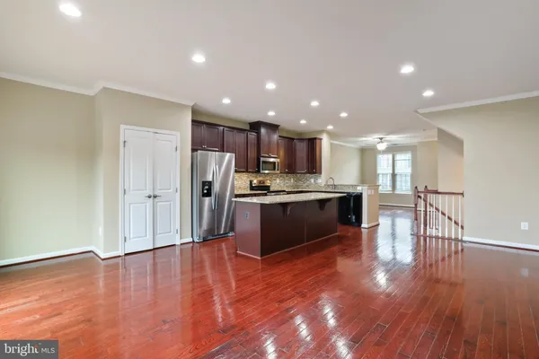 a large kitchen with stainless steel appliances granite countertop a large counter top a sink and a refrigerator