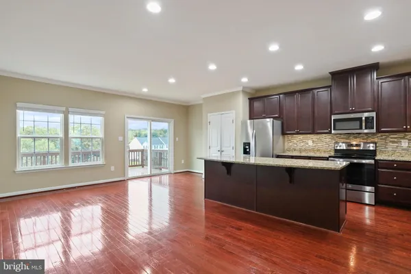a kitchen with granite countertop wooden floors a stove top oven a sink and dishwasher with wooden floor