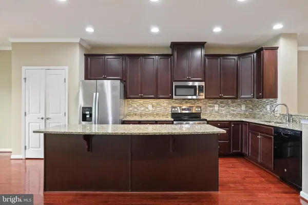 a kitchen with kitchen island granite countertop wooden cabinets and stainless steel appliances