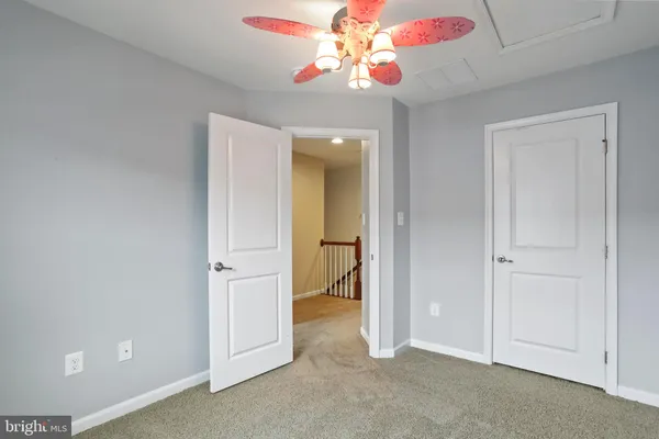 an empty room with a chandelier fan and closet