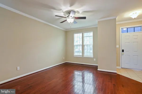 an empty room with wooden floor chandelier fan and windows