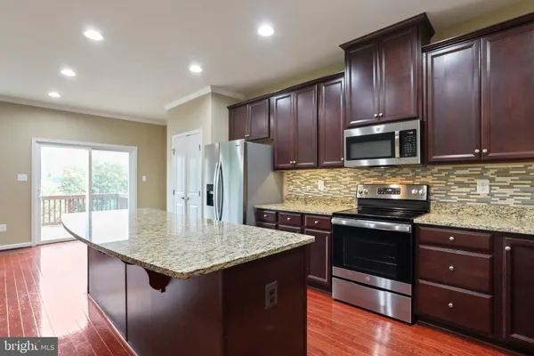 a kitchen with stainless steel appliances granite countertop a stove a refrigerator a sink a microwave and wooden cabinets